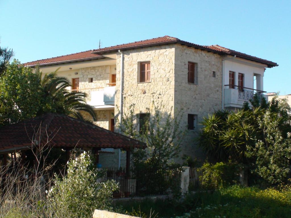 una gran casa de piedra con una valla delante en Venia Apartments, en Afitos