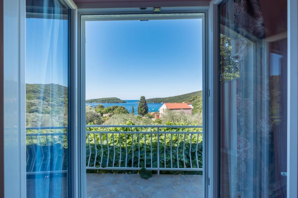 uma porta de vidro deslizante para uma varanda com vista para o oceano em Apartments Saulan em Molunat