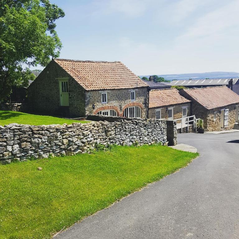 a stone house with a stone wall and a road at Prospect Farm Cottages in Allerston