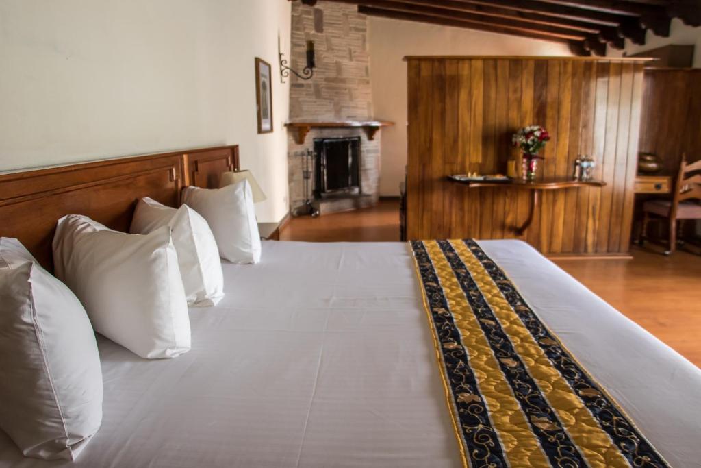 una camera da letto con un letto con cuscini bianchi e un camino di Hotel Posada Vista Bella a Morelia