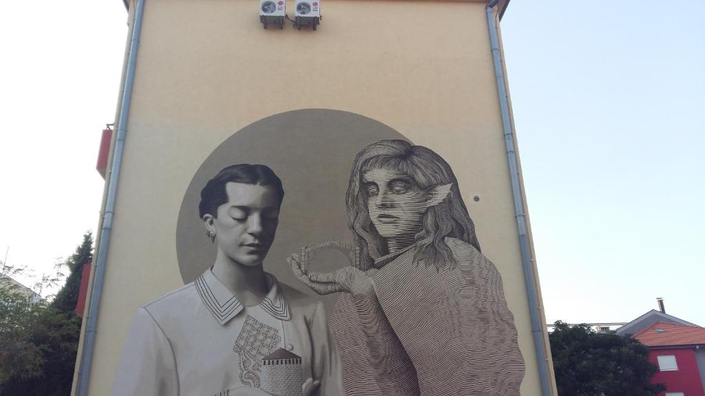 Un murale di un uomo e una donna sul lato di un edificio di Studio Dani a Mostar