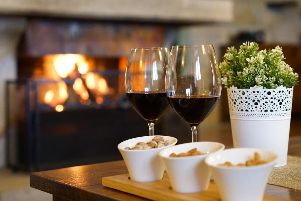 two glasses of wine and bowls of food on a table with a fireplace at Casa da Torre in Pico