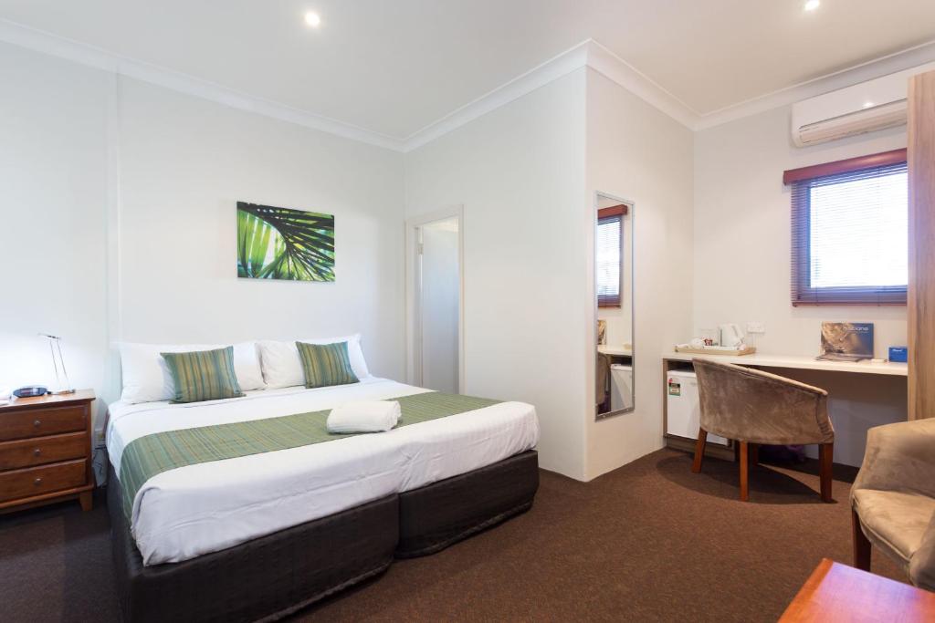 1 dormitorio con cama, escritorio y silla en Manly Hotel en Brisbane