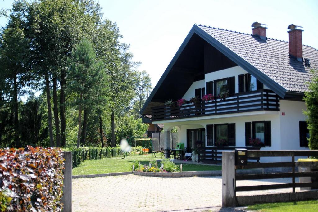 ein weißes Haus mit schwarzem Dach und einem Zaun in der Unterkunft Lake House Apartment in Medvode