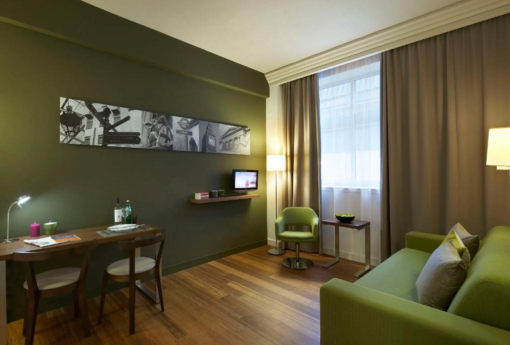 a living room with a green couch and a table at Citadines Holborn - Covent Garden London in London