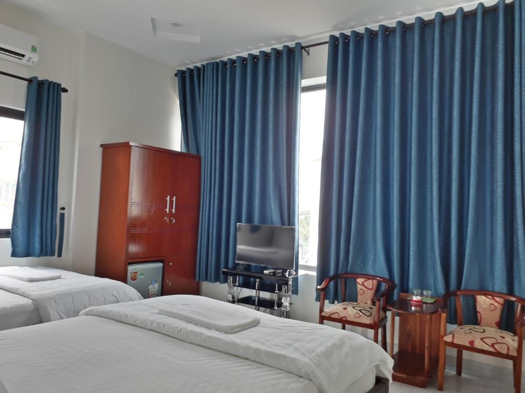 a bedroom with two beds and a television and blue curtains at Nice Hotel in Da Nang