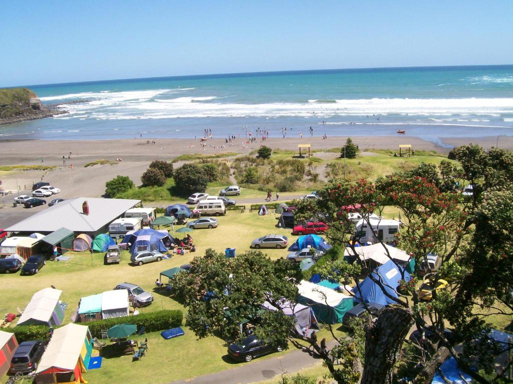 una vista aerea di una spiaggia con tende e persone sulla spiaggia di Opunake Beach Kiwi Holiday Park a Opunake