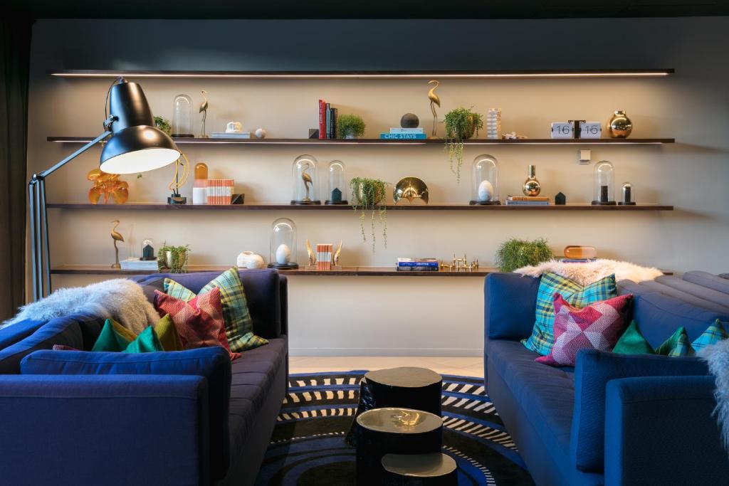 a living room with two blue couches and shelves at Naumi Auckland Airport Hotel in Auckland