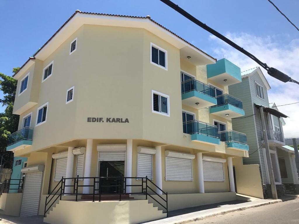 Las Flores的住宿－Luxury Karla Apartments，白色的建筑,设有蓝色的阳台,位于街道上