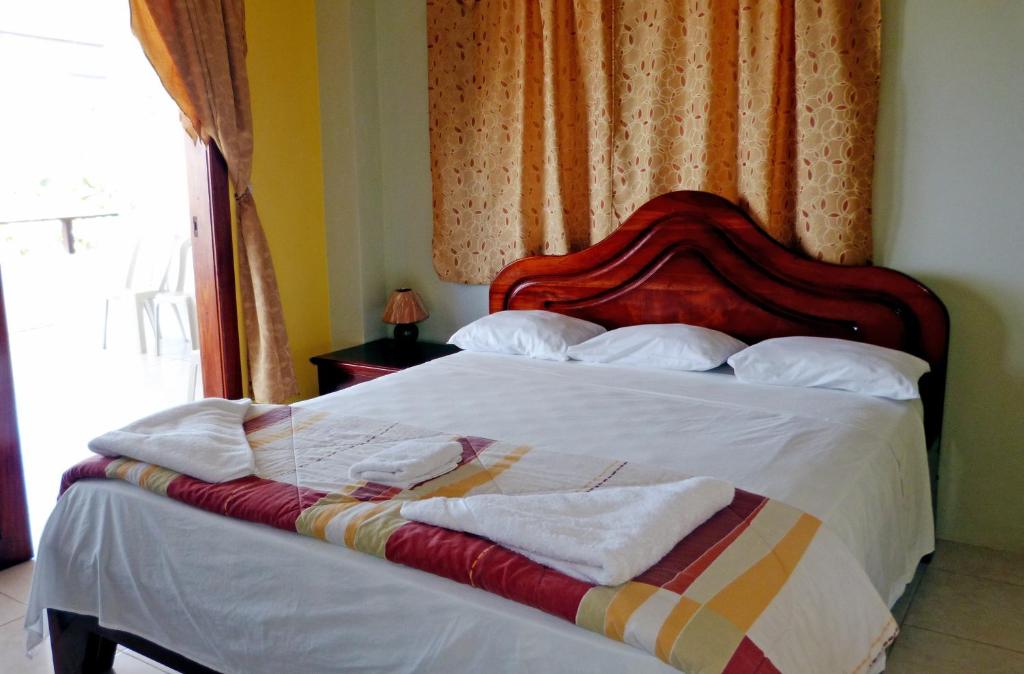 a bedroom with a bed with white sheets and pillows at Casa Los Delfines in Puerto Villamil