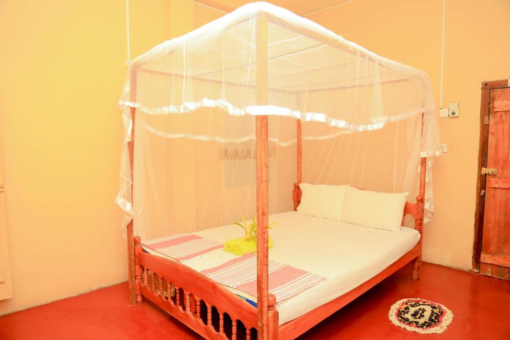 1 dormitorio con cama con dosel y sábanas blancas en Natural Cabanas, en Tangalle