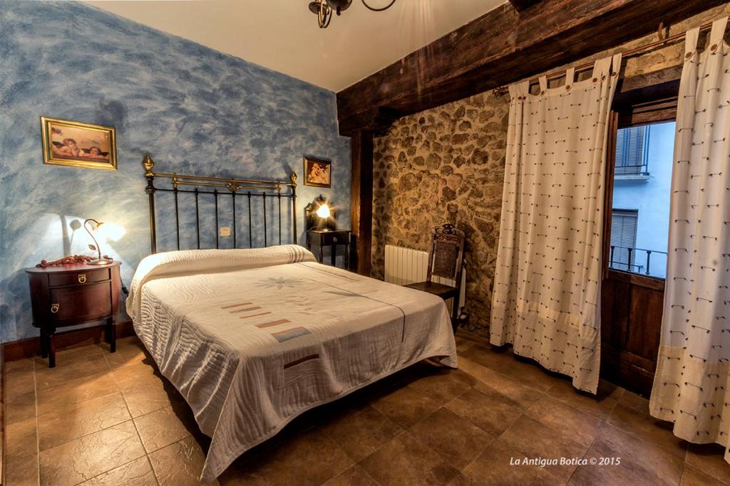 1 dormitorio con cama y pared de piedra en La Antigua Botica, en Pasarón
