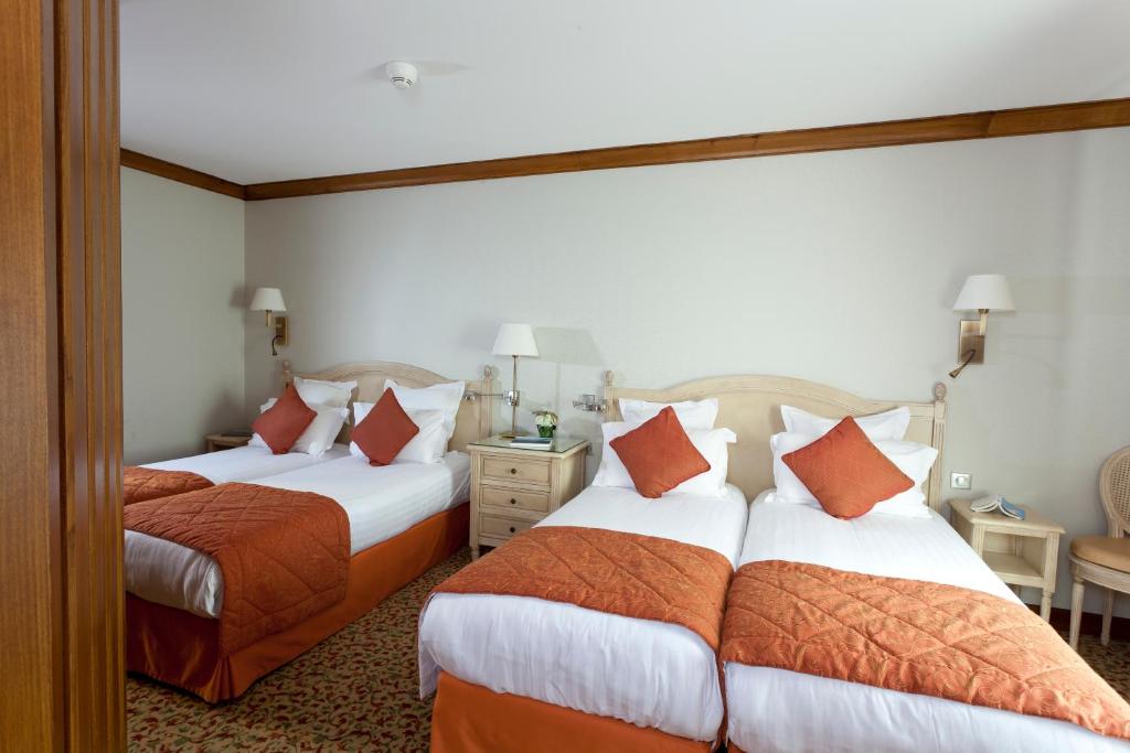 a hotel room with two beds with orange pillows at Auberge Saint Pierre in Le Mont Saint Michel