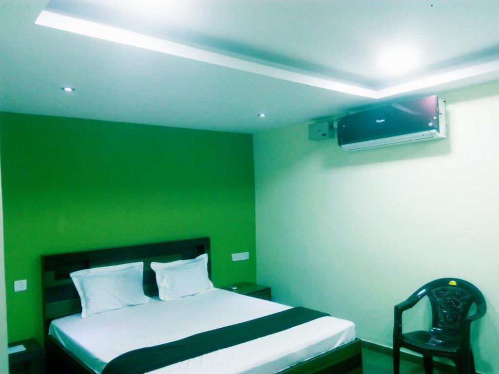 um quarto verde com uma cama e uma cadeira em Kempegowda Lodging & Boarding em Nelamangala
