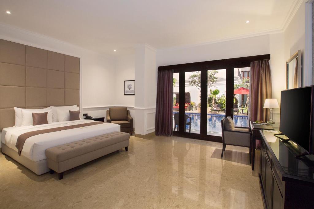 a hotel room with a bed and a television at Grand Palace Hotel Sanur - Bali in Sanur