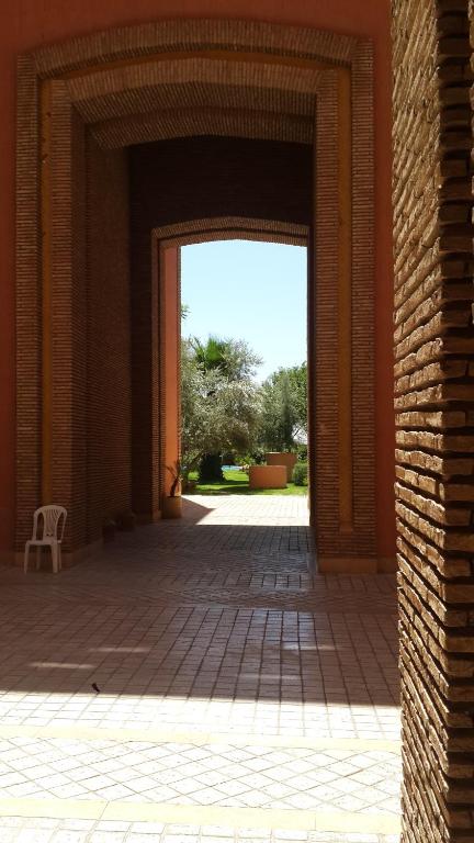 une porte ouverte menant à un bâtiment avec une chaise dans une cour dans l'établissement Ritaj Apartement, à Marrakech