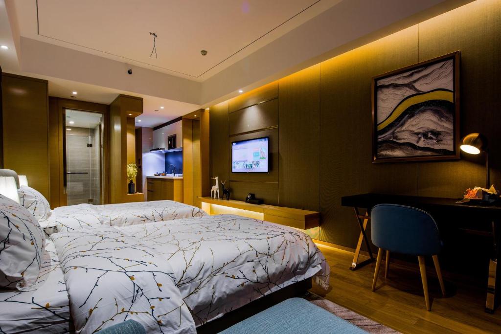 a bedroom with a bed and a desk and a television at Mai Ha Dun Lang De International Apartment in Guangzhou