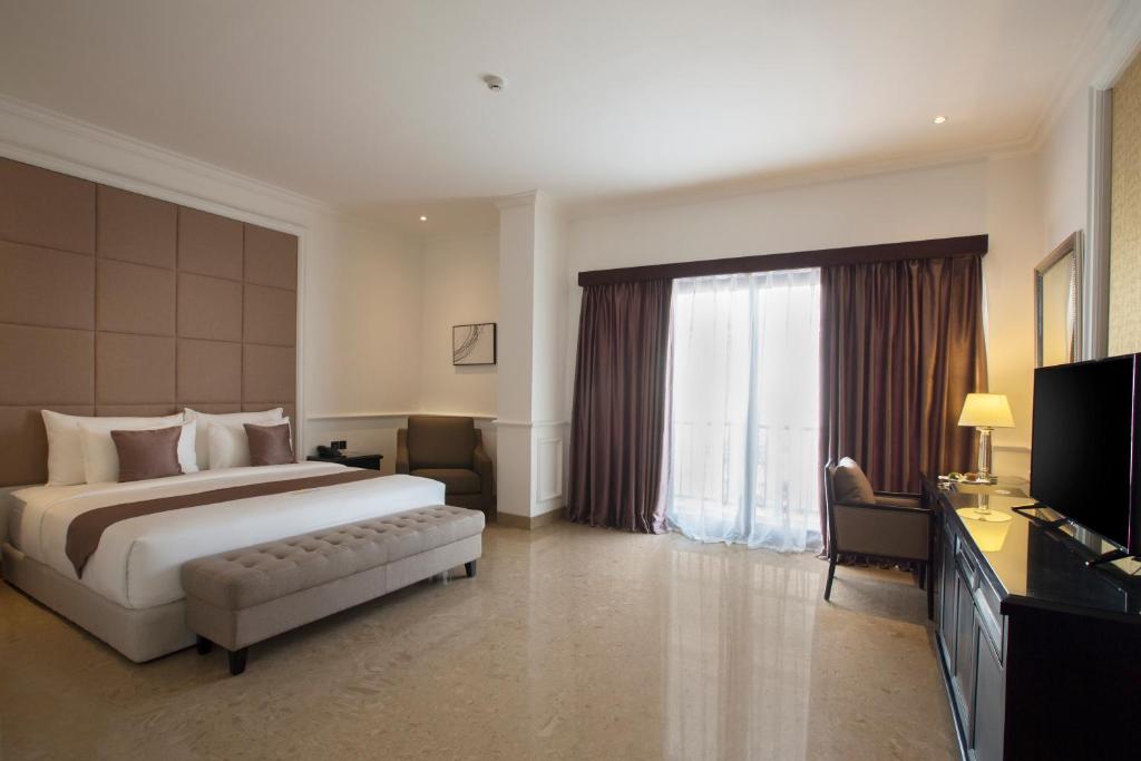a hotel room with a bed and a television at Grand Palace Hotel Sanur - Bali in Sanur