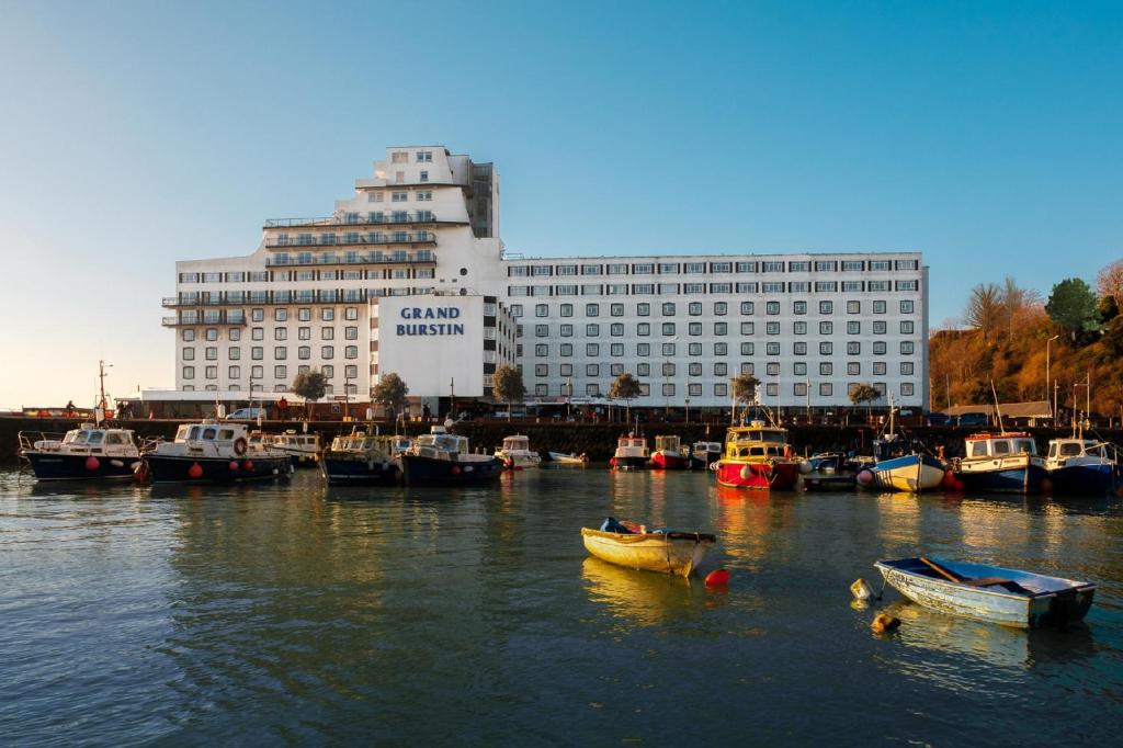 een groep boten in een haven met een gebouw bij The Grand Burstin Hotel in Folkestone