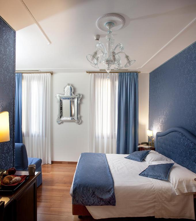 a blue bedroom with a bed and a chandelier at Hotel Ca&#39; D&#39;Oro in Venice