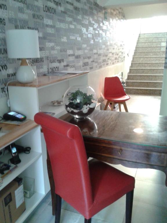 米蘭的住宿－馬耳他酒店，一间带桌子和两张红色椅子的用餐室