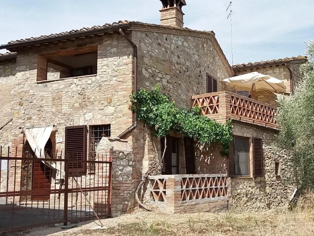 een oud stenen huis met een houten balkon bij Casa dei Borghi in Murlo