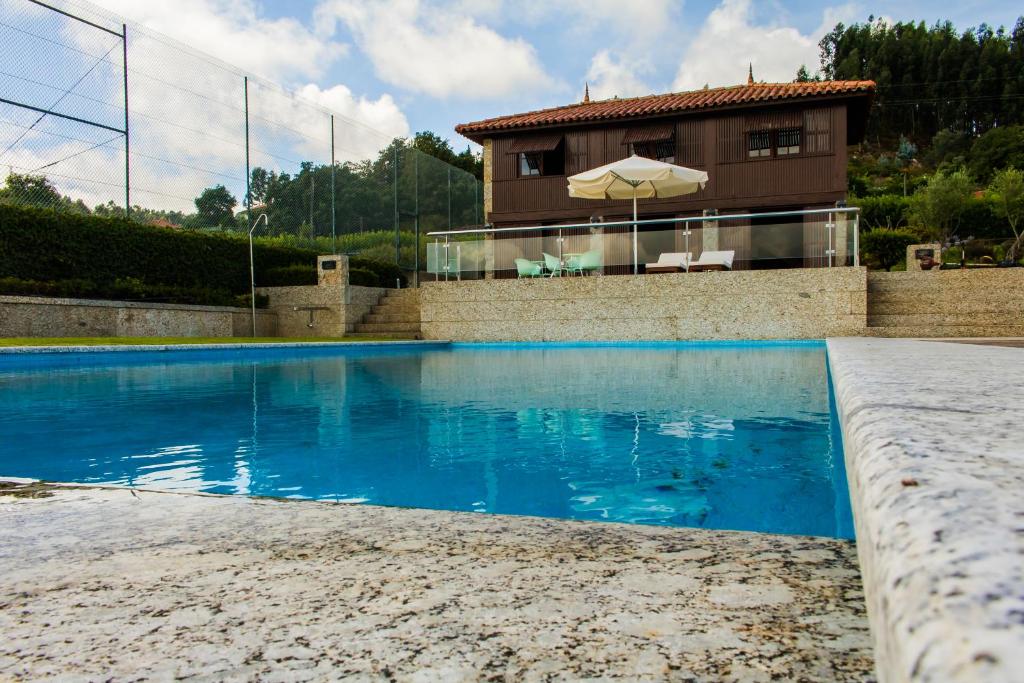 a swimming pool with a house in the background at Quinta da Eira do Sol in Guimarães