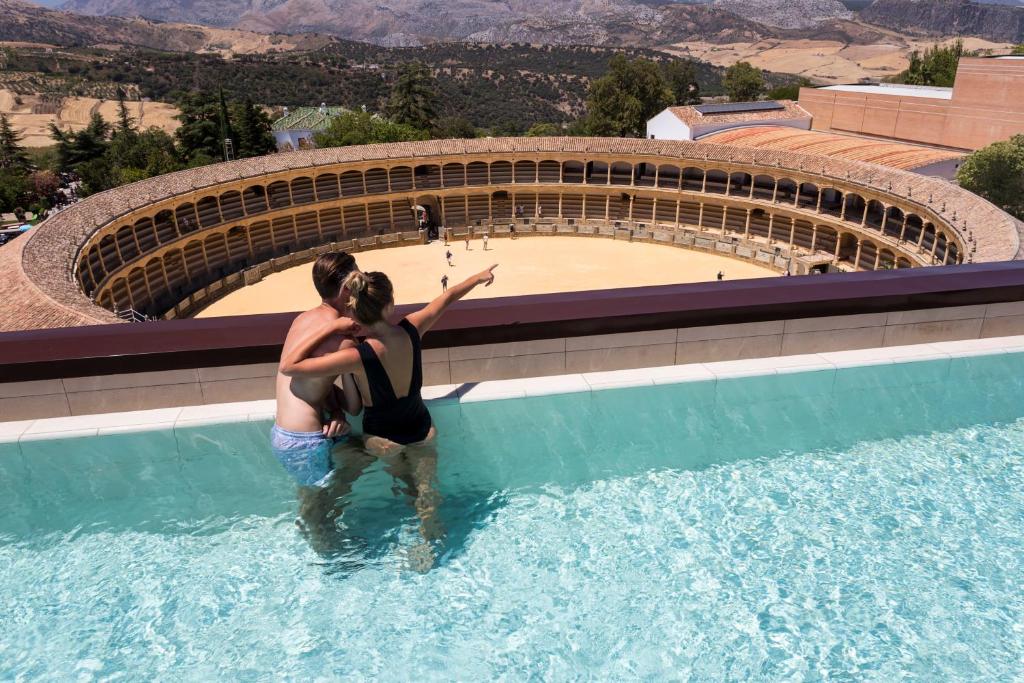 un homme et une femme debout dans une piscine dans l'établissement Catalonia Ronda, à Ronda