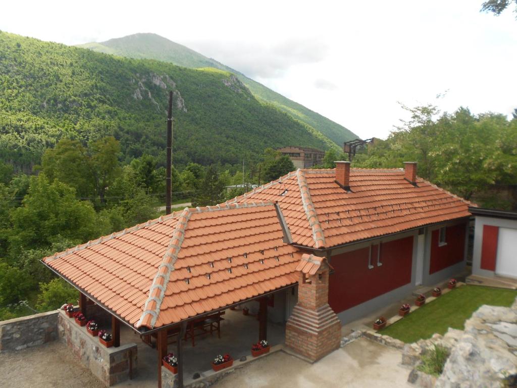 a house with a red roof with mountains in the background at Vikendica RTANJ in Rtanj