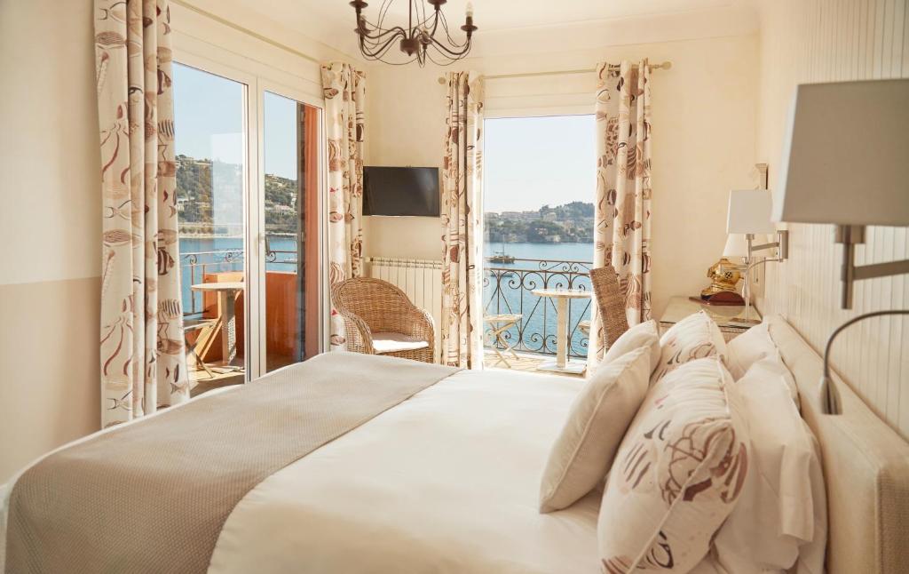 a bedroom with a bed with a view of the ocean at Welcome Hotel in Villefranche-sur-Mer