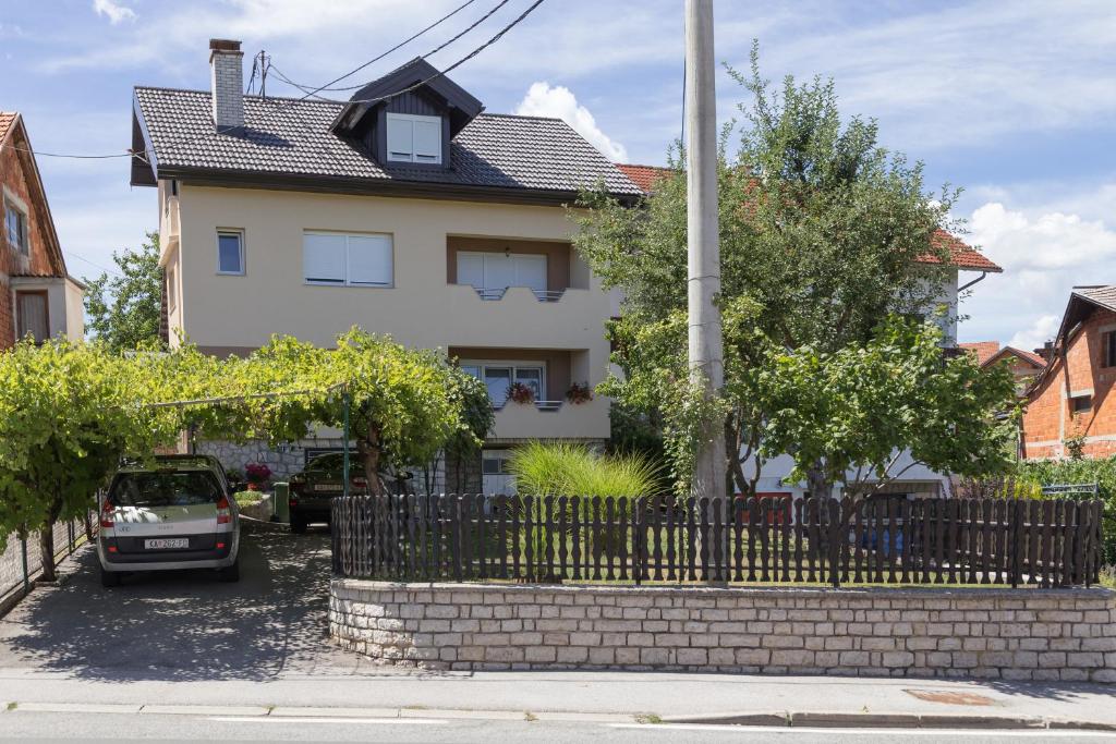a house with a fence and a car parked in front at IRIS Room & Apartment in Slunj