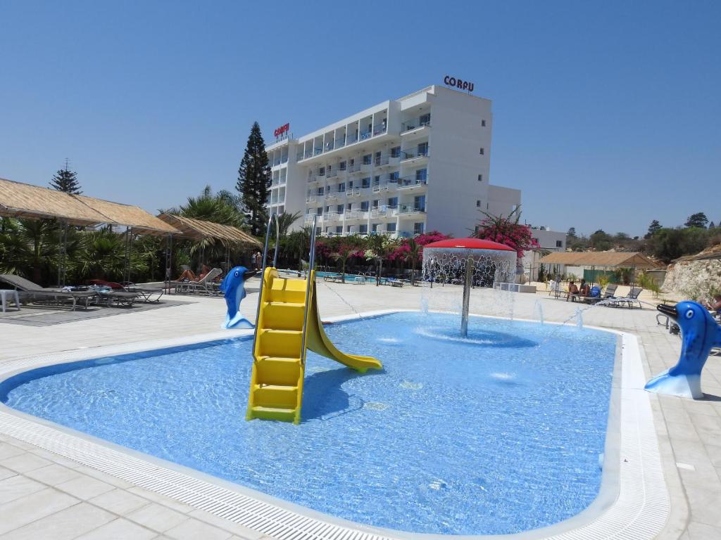 a swimming pool with a slide in the water at Corfu Hotel in Ayia Napa