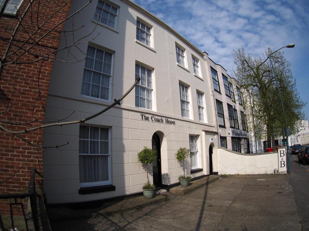 een wit gebouw met een bord aan de zijkant bij The Coach House in Canterbury
