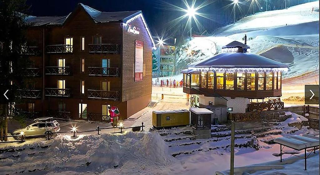 un edificio con un cenador en la nieve por la noche en ZimaSnow Ski & Spa Club, en Bukovel
