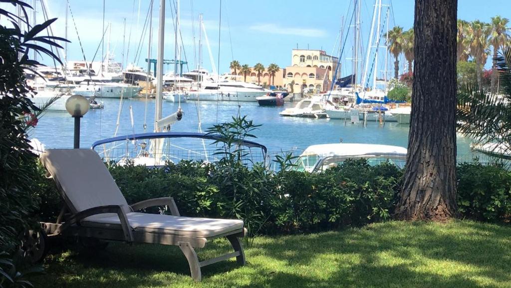 una panchina seduta sull'erba accanto a un porto turistico di Portorosa Villa Sole a Furnari