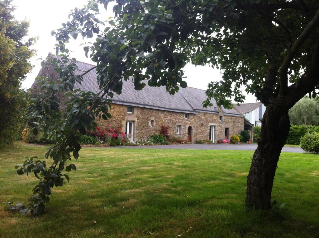 une maison en briques avec un arbre dans la cour dans l'établissement La Longere d'Helene, à Lauzach