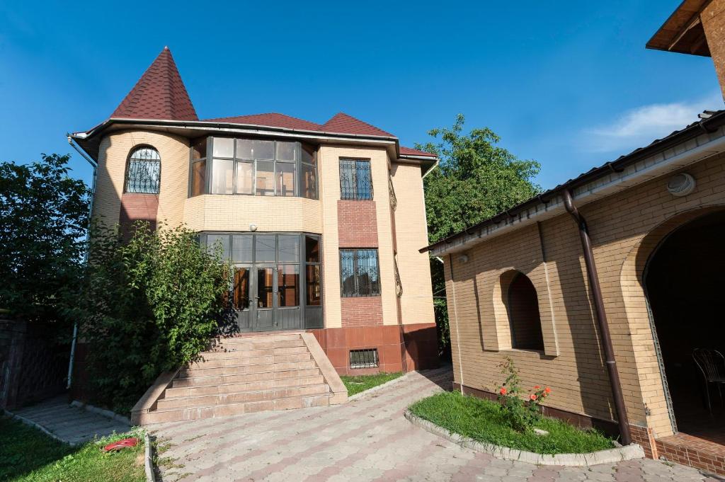 a large brick house with a staircase in front of it at Dostyk Hostel in Almaty
