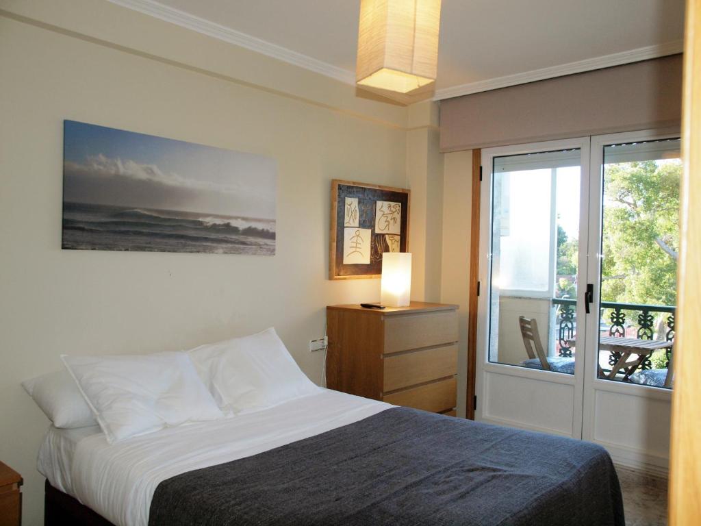 ビラガルシーア・デ・アロウサにあるApartamento Compostela Playaのベッドルーム1室(ベッド1台付)、スライド式ガラスドアが備わります。