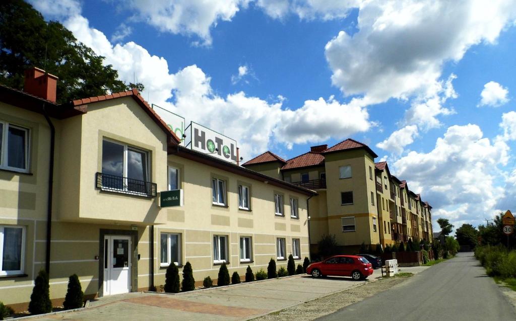 ein rotes Auto, das vor einem Gebäude parkt in der Unterkunft EndHotel Bielany Wroclawskie in Bielany Wrocławskie