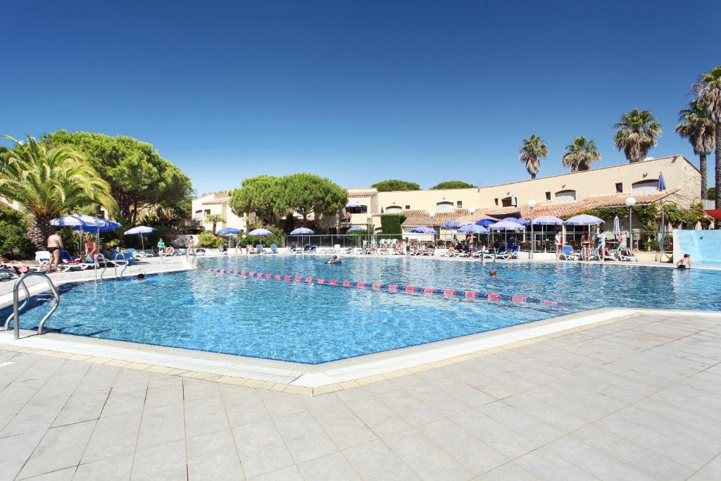 une grande piscine avec des chaises et des parasols dans l'établissement Résidence Odalys Saint Loup, au Cap d'Agde