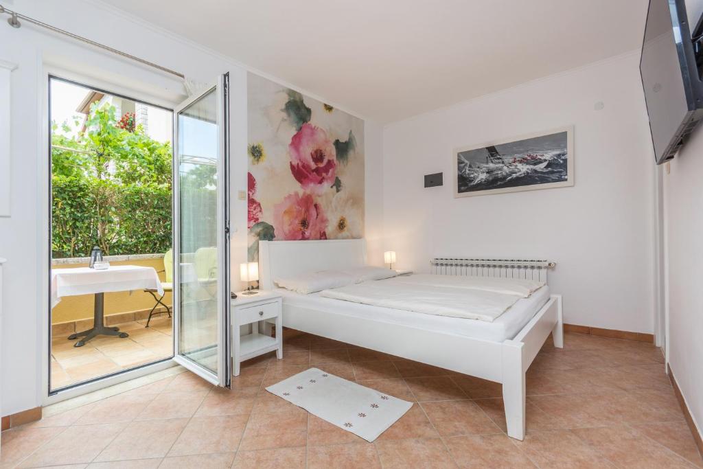 a white bedroom with a bed and a window at Guesthouse Casa Nova in Poreč