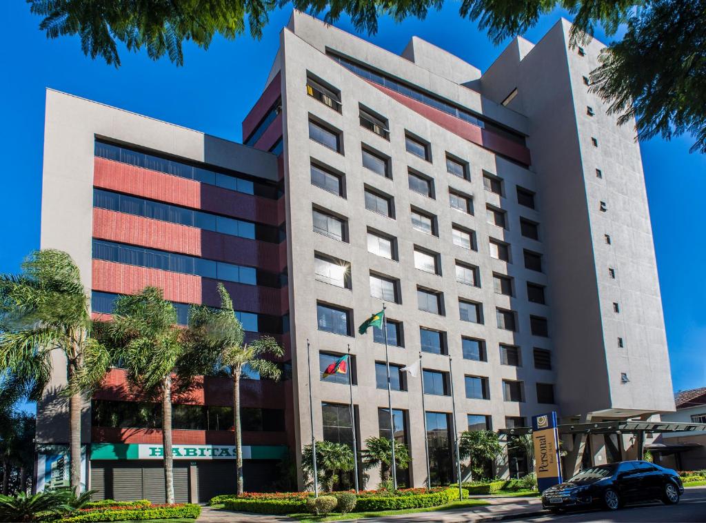un grand bâtiment blanc avec des palmiers devant lui dans l'établissement Tri Hotel Executive Caxias, à Caxias do Sul