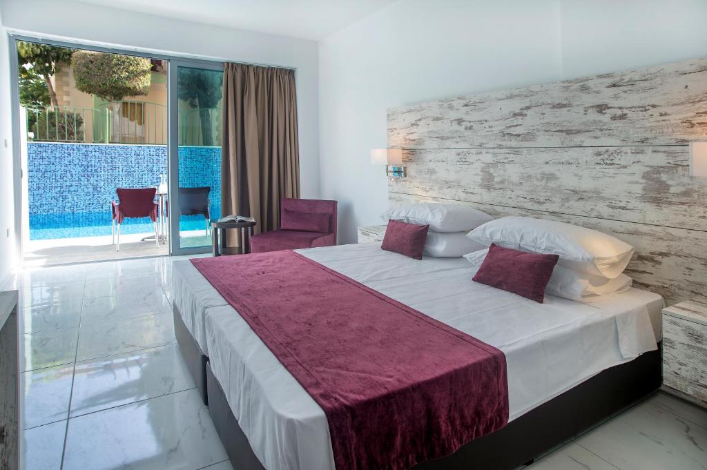 a hotel room with a bed and a large window at Freij Beach Hotel Adults Only in Ayia Napa