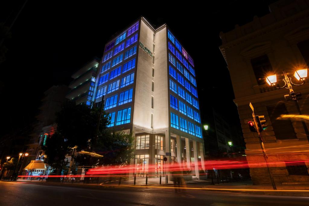 un bâtiment éclairé dans une rue de la ville la nuit dans l'établissement Brown Kubic, a member of Brown Hotels, à Athènes