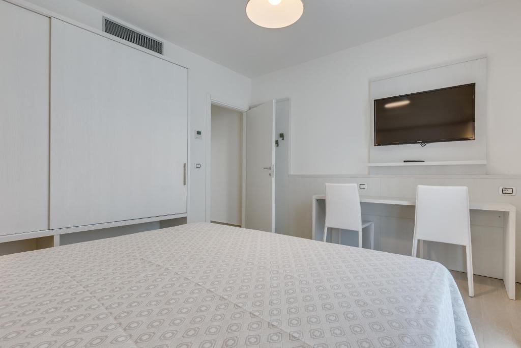 a white bedroom with a white bed and white chairs at Hotel Ambassador in Caorle
