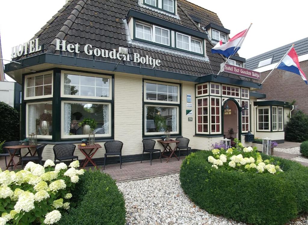 a let gourmet building with tables and chairs in front of it at Hotel Het Gouden Boltje in De Koog