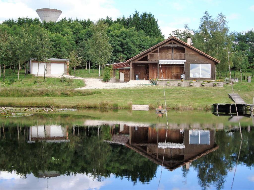 a house with a pond in front of it at Lieux-au-lac in Augignac