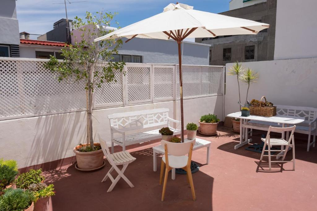 eine Terrasse mit einem Sonnenschirm, einem Tisch und Stühlen in der Unterkunft Casa María Cristina 3 in Santa Cruz de Tenerife