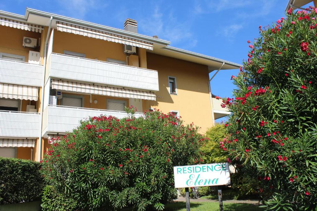 una señal frente a un edificio con árboles en flor en Appartamenti Elena, en Grado