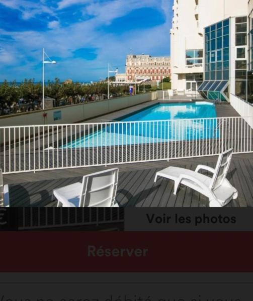 une piscine avec deux chaises blanches sur un balcon dans l'établissement Studio Victoria Centre Grande Plage and Pool, à Biarritz